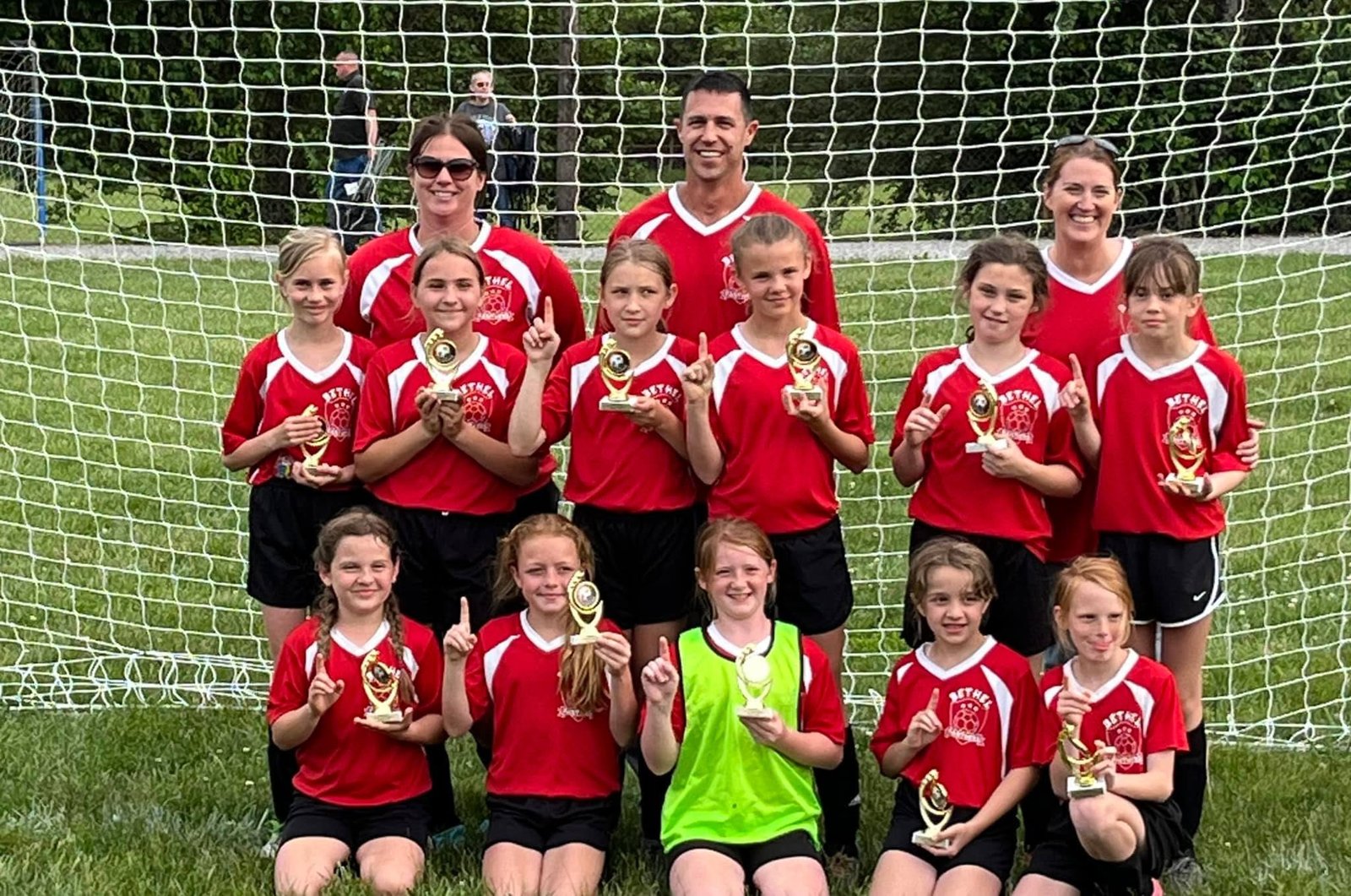 Bethel girls soccer team with trophies in front of the goal